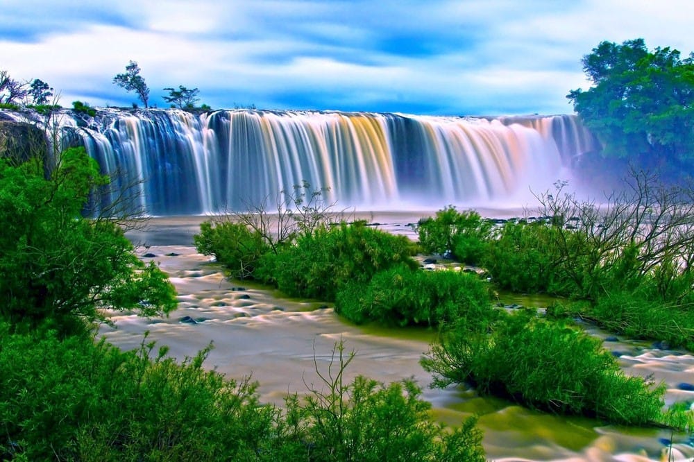 qué ver en Canadá Cataratas del Niágara en Canadá con vegetación delante e iluminación multicolor en el agua